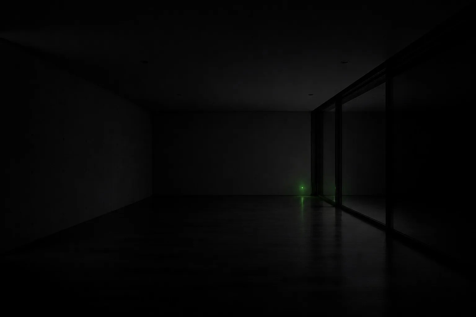 A dark empty room with a single small indicator light glowing in the corner